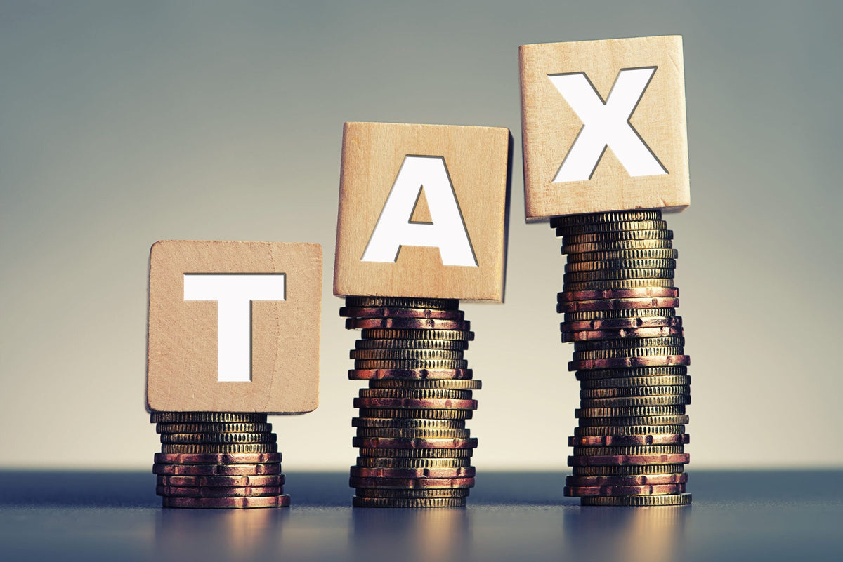 Houten blokken met het woord TAX op stapels munten